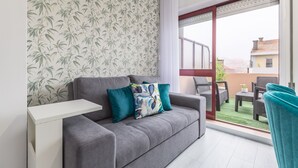 A grey sofa with teal cushions, a white side table, and a view of a balcony with outdoor furniture. - Paradise Porto apartment with terrace in the center of Porto (Porto)
