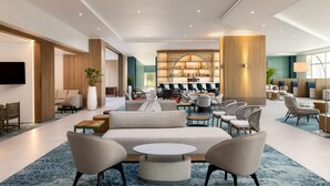 A spacious lobby with a bar area, seating arrangements, and a large screen. - Courtyard by Marriott Curacao (Willemstad)