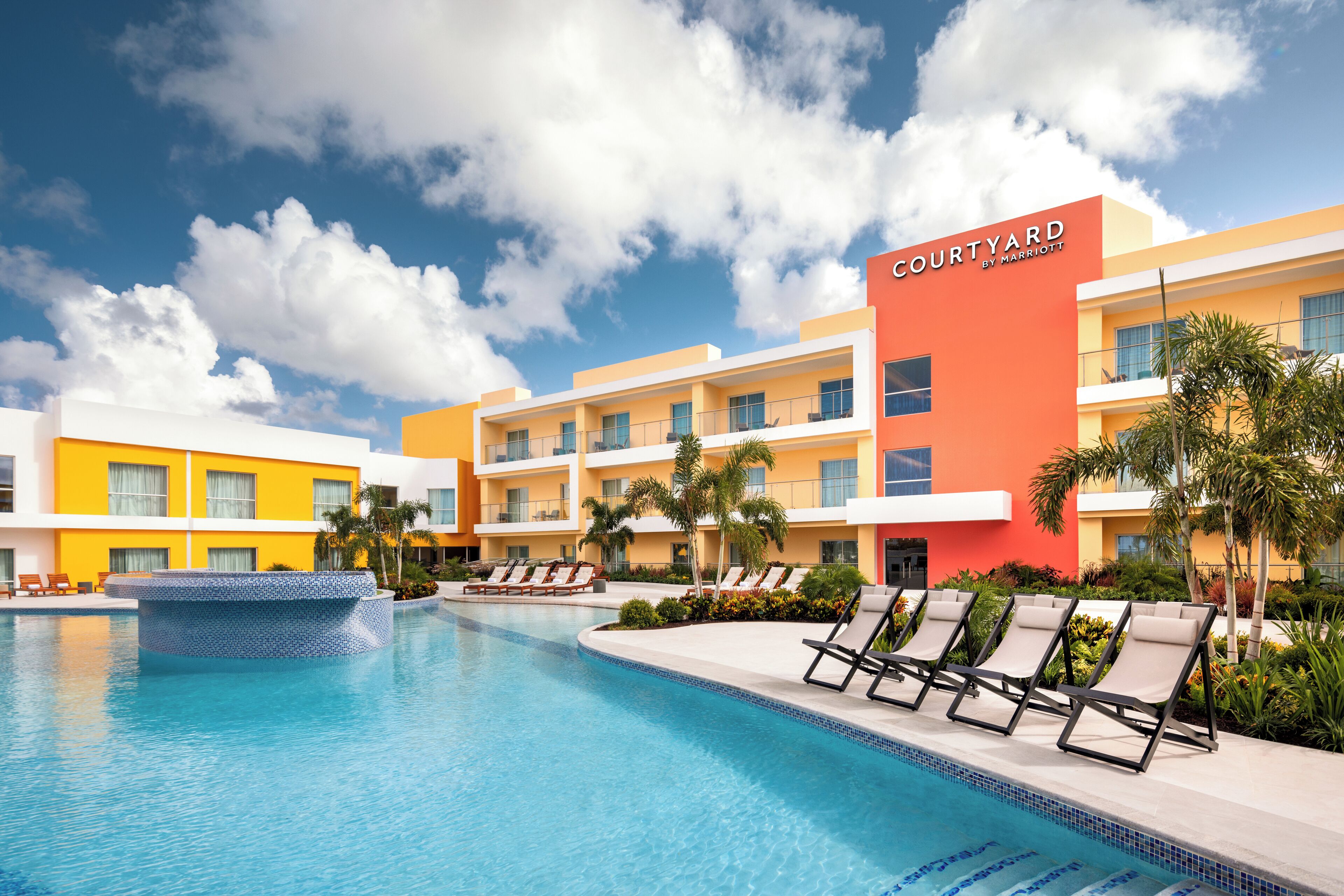 A hotel courtyard with a swimming pool, lounge chairs, and a building with 'Courtyard by Marriott' signage.
