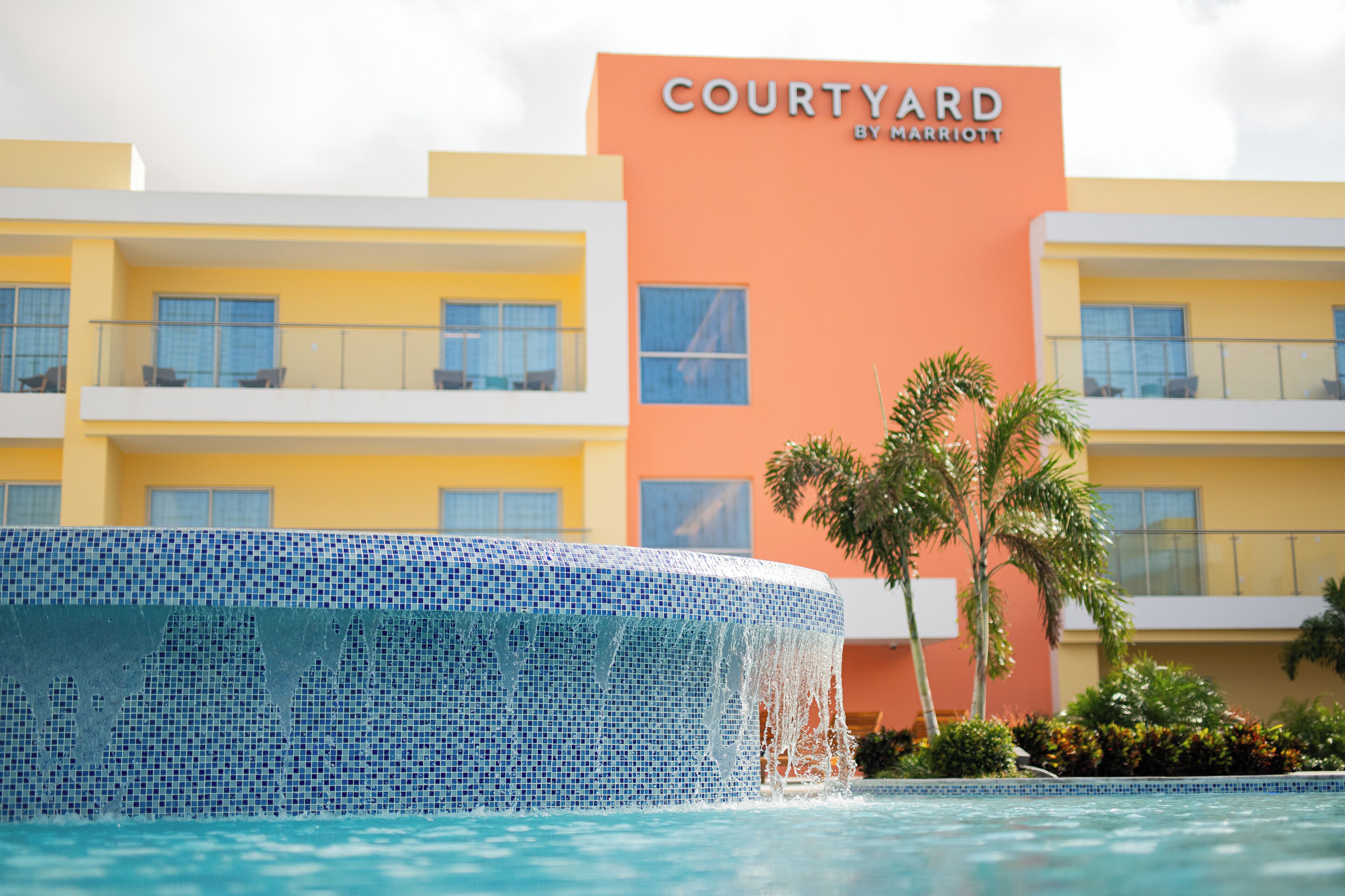 A Courtyard by Marriott hotel with a pool area featuring a mosaic tile edge.