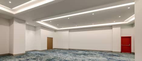 Una habitación amplia con alfombra estampada, iluminación empotrada y una puerta roja.