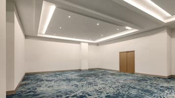A spacious room with a high ceiling, recessed lighting, and a patterned carpet.