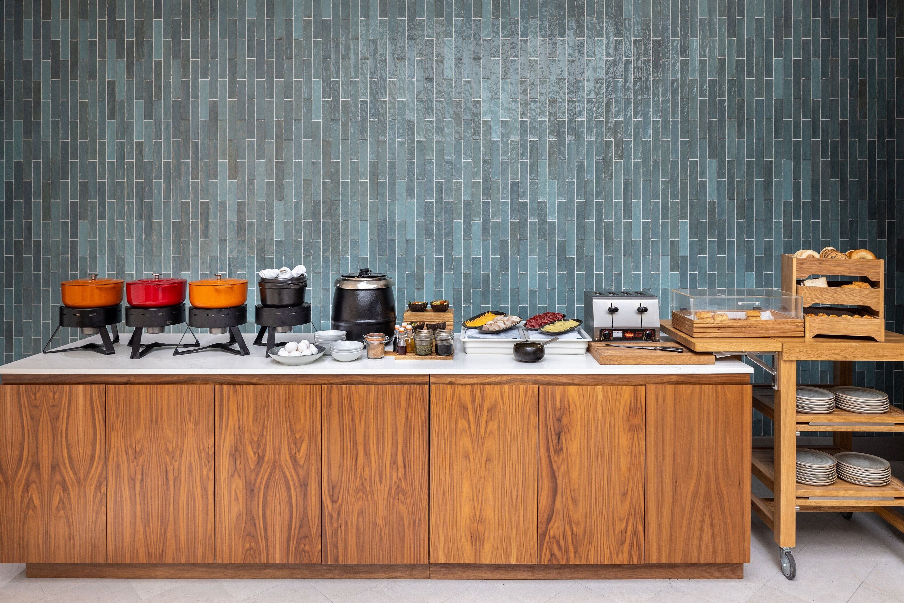 A kitchen counter with various appliances and food items, a wooden cabinet, and a tiled backsplash.