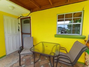 A room with a yellow wall, a window with a view, a table, and two chairs.