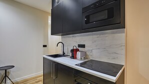 A modern kitchen with a black stove, a microwave, and a sink with a faucet. - Meslay 6 - One Bedroom Apartment, Sleeps 4 (Paris)