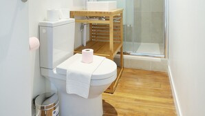 Et lille badeværelse med toilet, håndvask og bruser.