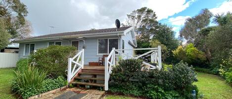 A single-story house with a front porch, a satellite dish, and a garden with various plants and shrubs.
