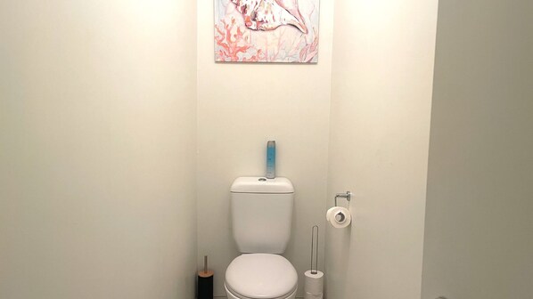 A bathroom with a toilet, a toilet paper holder, and a hand sanitizer dispenser.