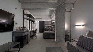 Un salon moderne comprenant un canapé, un téléviseur, une table basse et un coin cuisine avec un réfrigérateur et un four à micro-ondes.