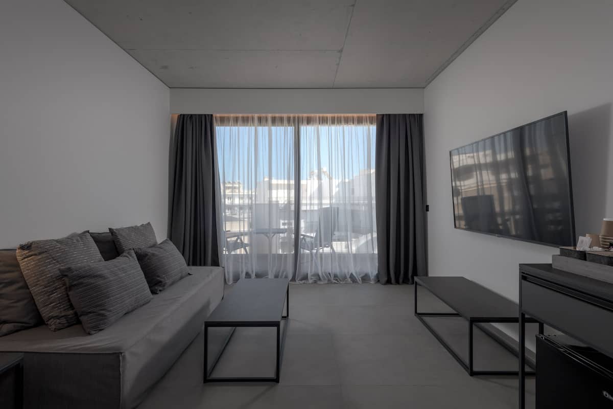 Un soggiorno moderno con divano, televisione e vista sul balcone.