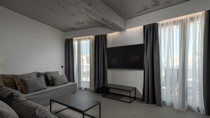 Un salon moderne avec un canapé, une table basse et un téléviseur à écran plat fixé au mur.