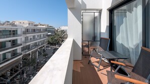 Un balcon avec vue sur le paysage urbain, une porte vitrée et des sièges d’extérieur.
