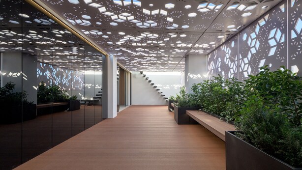 Un intérieur moderne avec un plancher en bois, un plafond au design géométrique et des plantes d’intérieur.