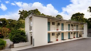 A two-story motel with a flat roof, multiple balconies, and potted plants. - CPA Quick Easy Virtual Check In Perfect for Business Professionals (Atlanta)