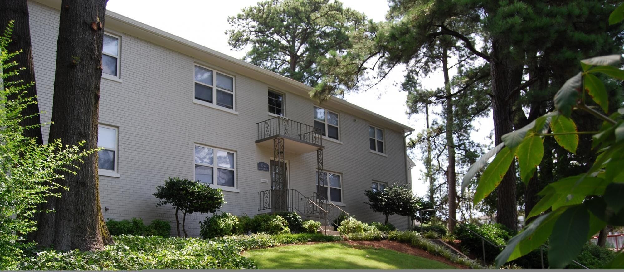 A multi-story building with a brick facade, a central staircase, and a small balcony.