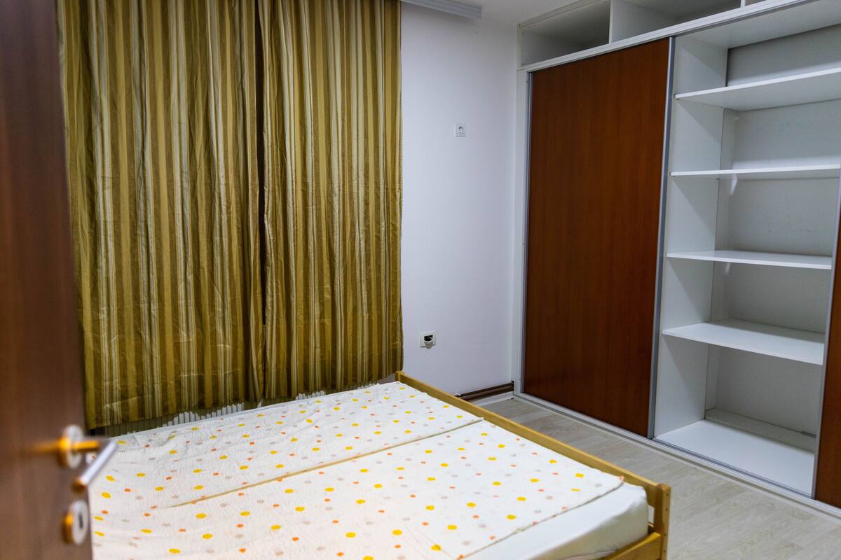 A bedroom with a bed, a wardrobe, and a built-in shelf unit.
