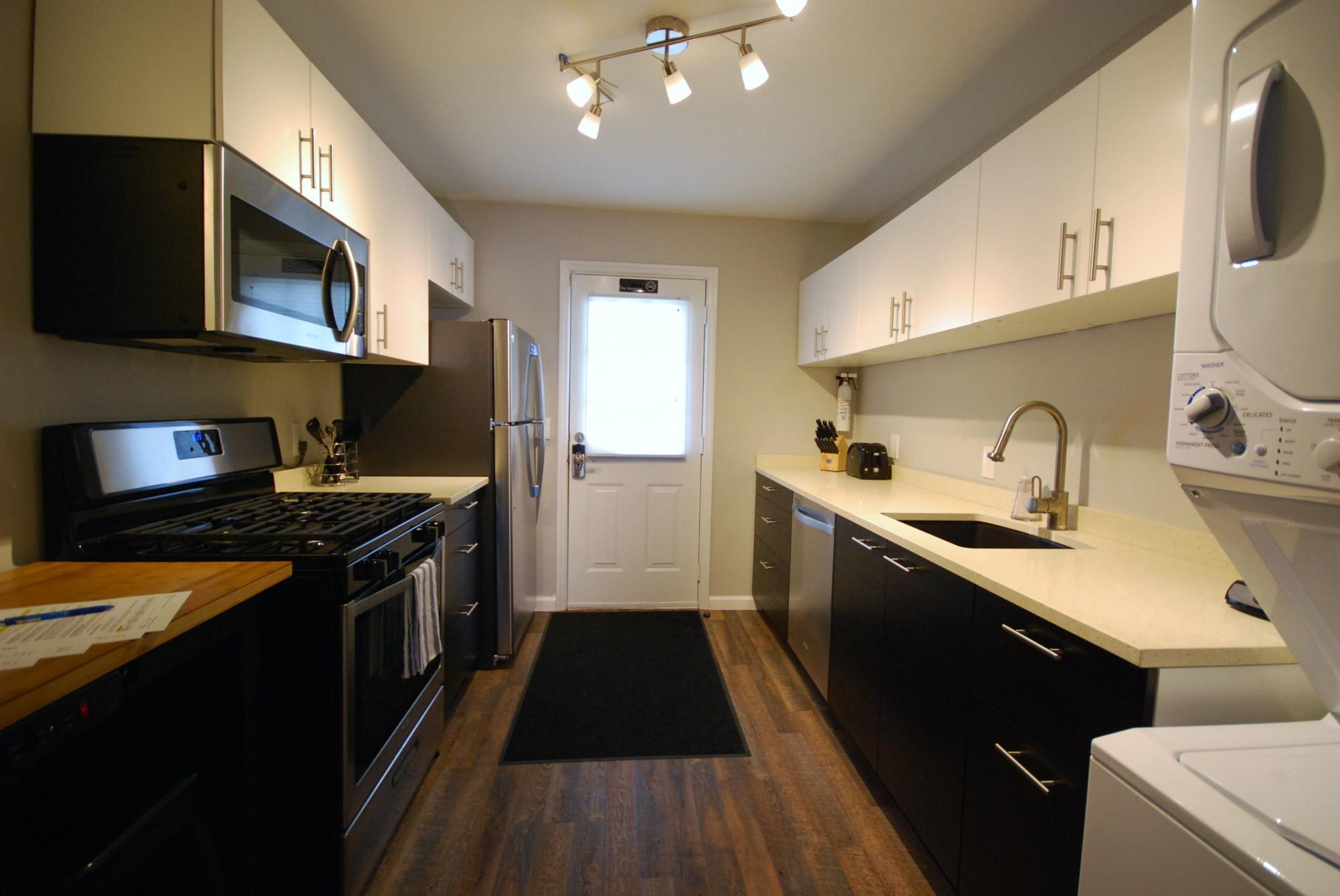 A modern kitchen with stainless steel appliances, a black stove, and a white countertop.