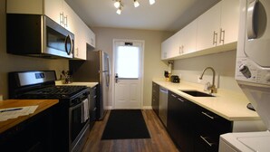 A modern kitchen with stainless steel appliances, a black stove, and a white countertop. - B2bc Convenient Condo Perfect for Long Term Stay Near Shepherd Center (Atlanta)