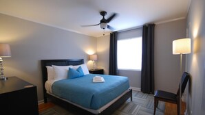 A hotel room with a bed, a desk, a chair, a ceiling fan, and a window with curtains. - B2bc Convenient Condo Perfect for Long Term Stay Near Shepherd Center (Atlanta)