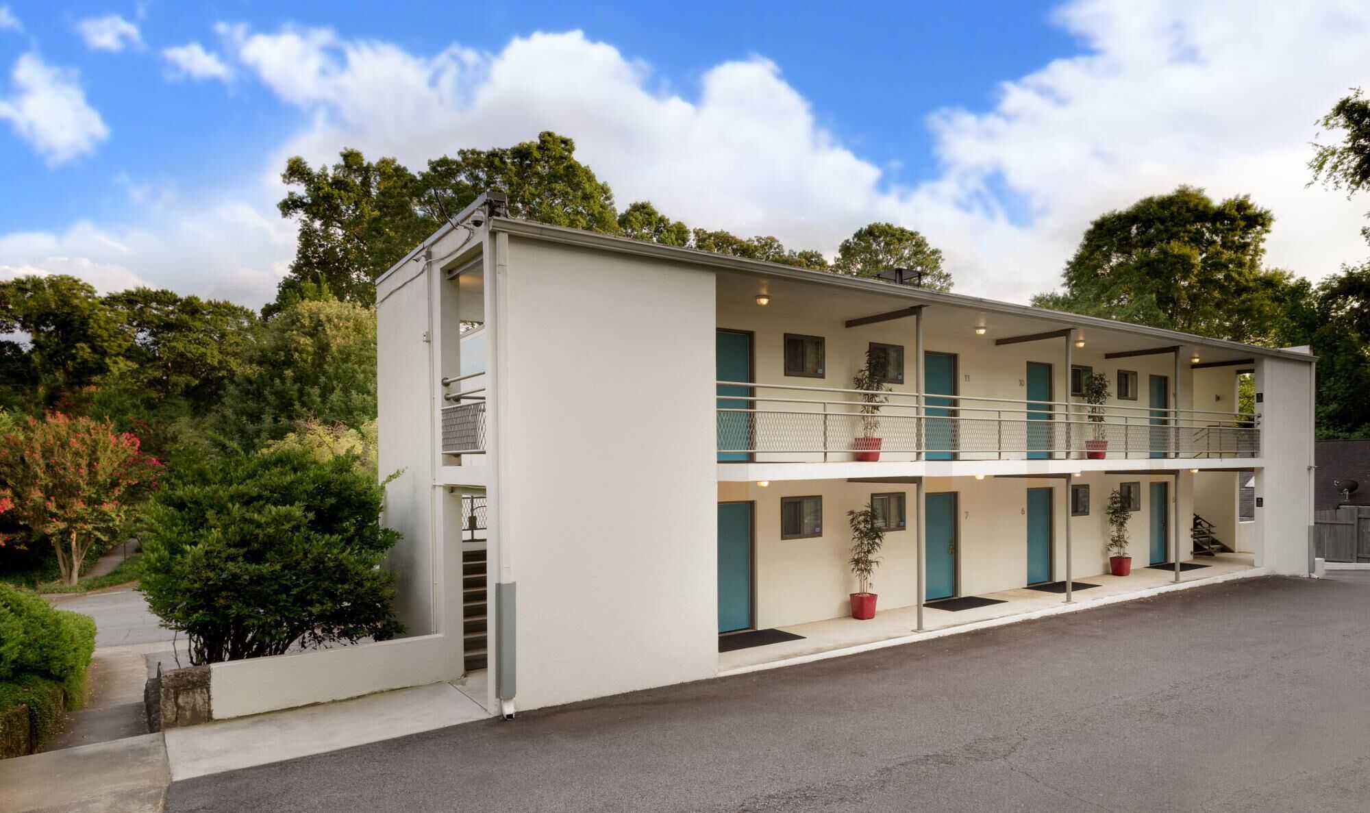 Un motel à deux étages, doté d’un toit plat, de nombreux balcons et de plantes en pot.