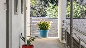 A corridor with a concrete floor, a red potted plant, a blue potted plant, and a metal railing. - CCL Professional Studio w Wi-fi Perfect for Business Travelers (Atlanta)