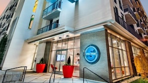 Ein modernes Hotel mit einer auffälligen Neonreklame, mehreren Balkonen und einem gut beleuchteten Eingang.