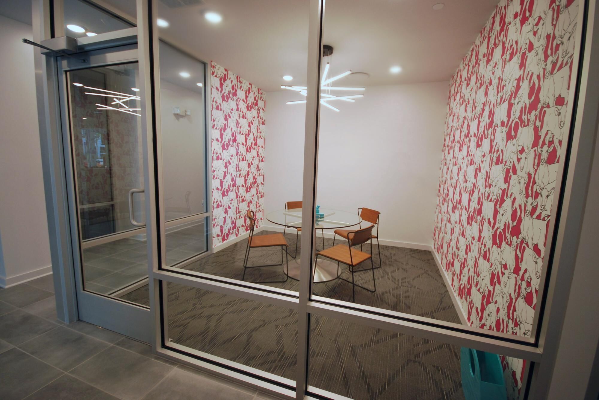A modern meeting room with glass partitions, a round table, and four chairs.
