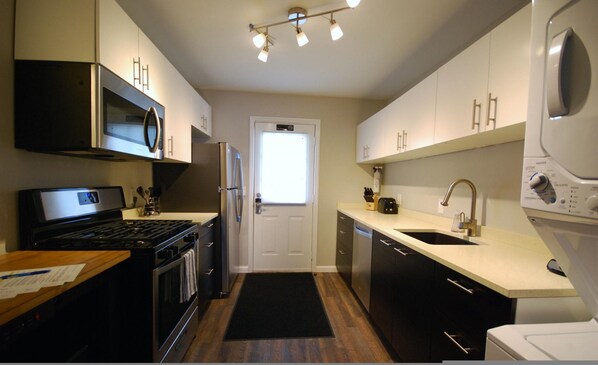 A compact kitchen with a microwave, stove, refrigerator, sink, and dishwasher.