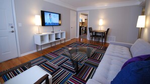 Un salon moderne avec un canapé, une table basse et un téléviseur fixé au mur.