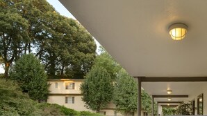 A covered outdoor area with a light fixture, a door with a number, and a building in the background. - CCD Convenient Studio Only Blocks From Piedmont Hospital (Atlanta)