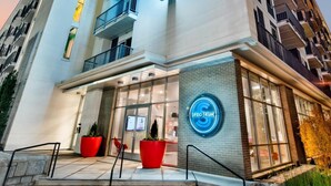 A modern hotel with a prominent neon sign, a glass entrance, and a brick facade. - S2ba Modern 2-br Walkable in Midtown 1 Block From Marta (Atlanta)