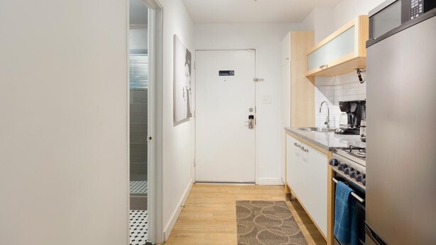 A narrow kitchen with a refrigerator, stove, and coffee maker. A door with a 'No Smoking' sign is visible. - CPH Secluded Studio Safe Serene and Serviced (Atlanta)