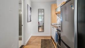 A modern kitchen with a stainless steel refrigerator, wooden cabinets, and a built-in oven. - CPB Quiet Studio Perfect for Travel Nurses (Atlanta)