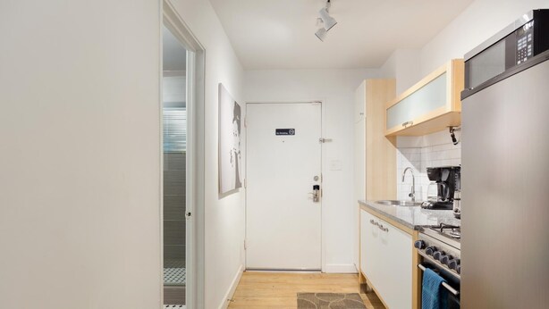 A compact kitchen with a refrigerator, stove, and sink. A 'No Smoking' sign is visible on the door. - CPB Quiet Studio Perfect for Travel Nurses (Atlanta)