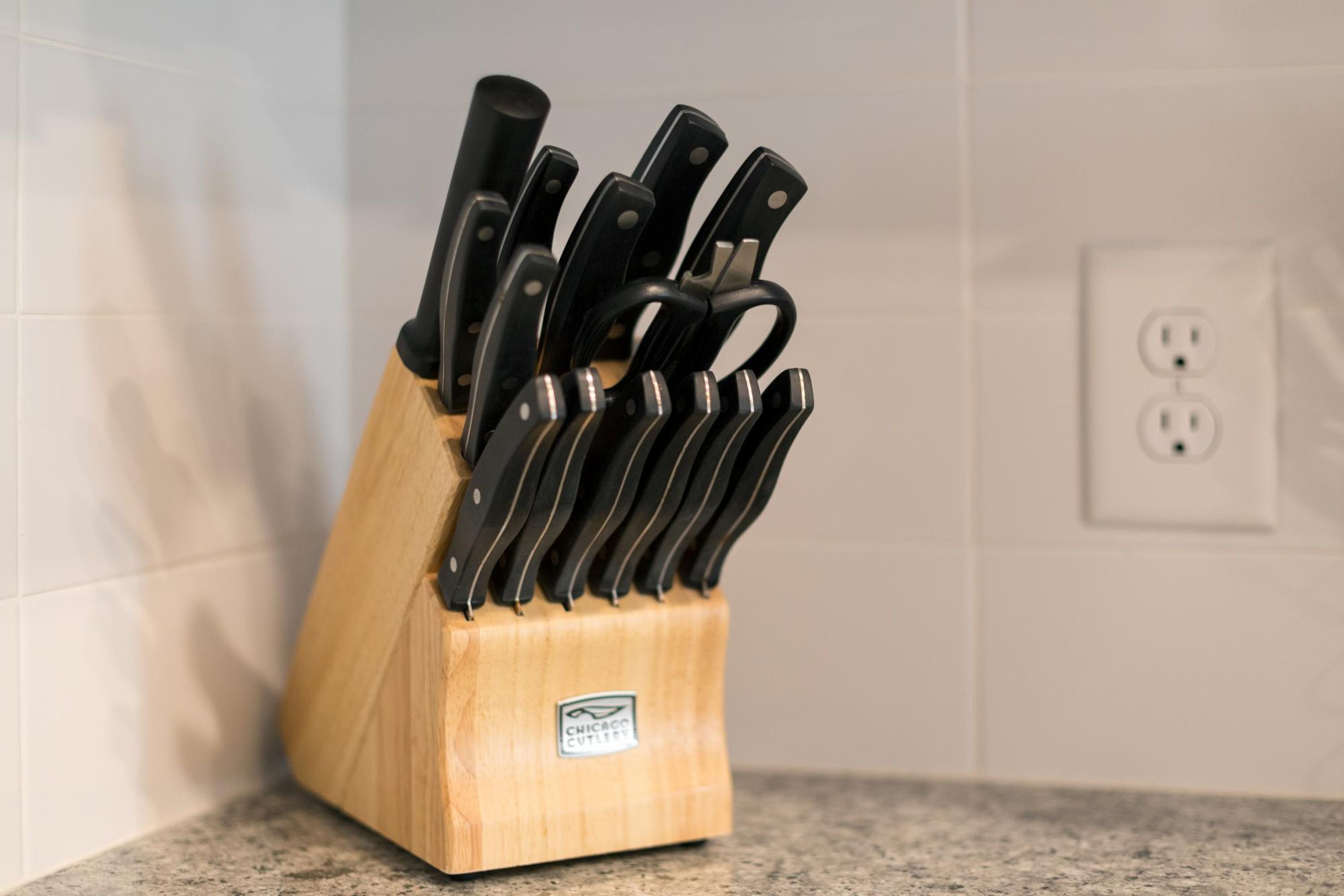A wooden knife block with multiple knives on a kitchen counter.