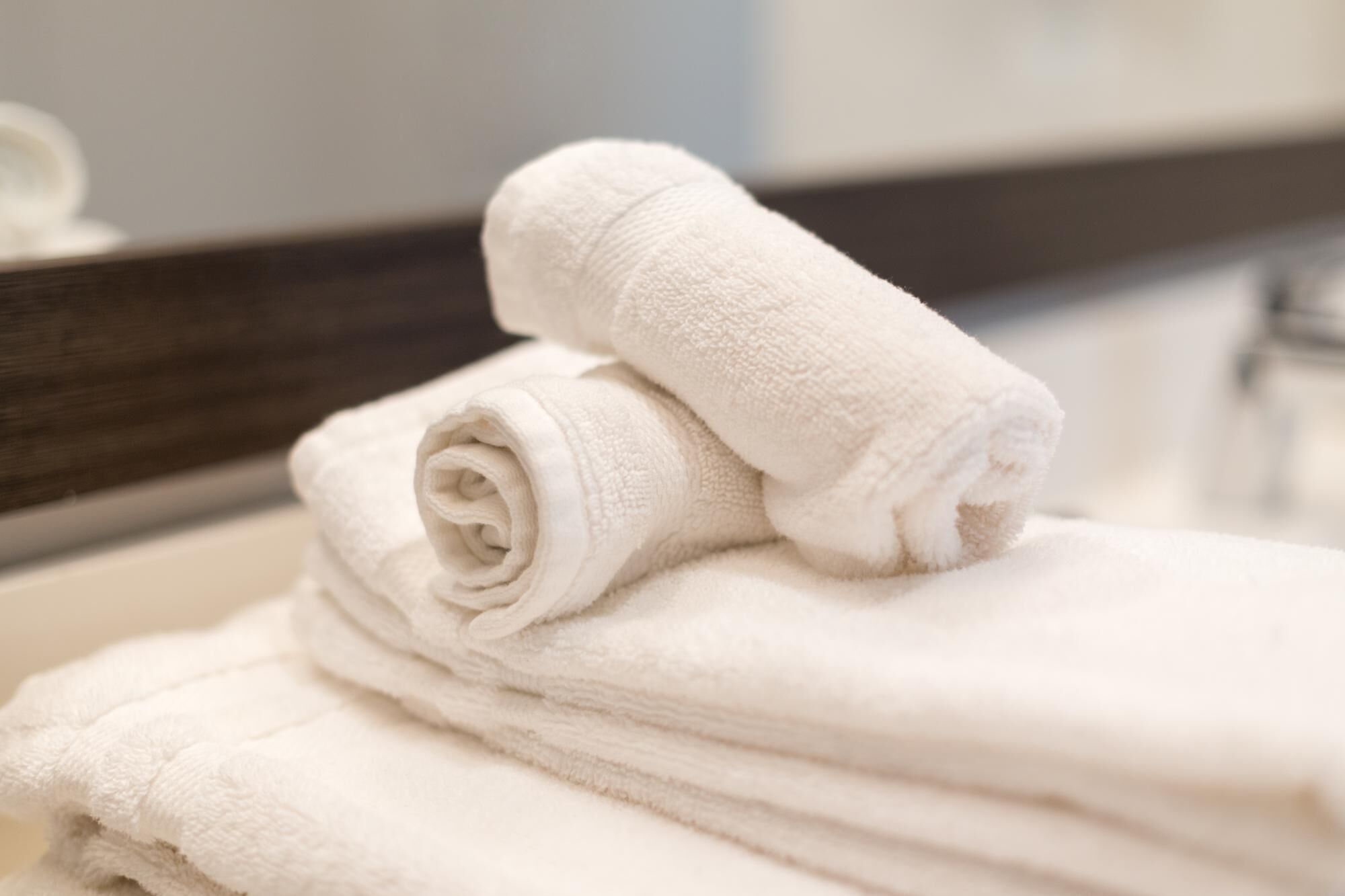 Une pile de serviettes blanches est posée sur le comptoir de la salle de bain.