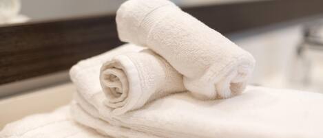 Une pile de serviettes blanches est posée sur le comptoir de la salle de bain.