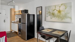 A modern kitchen with a refrigerator, microwave, and oven. There is a dining table with chairs and a large floral artwork on the wall. - CPG Serviced Studio w Full Kitchen in Quiet Neighborhood (Atlanta)