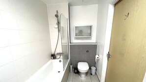 A small bathroom with a bathtub, toilet, and a shower. - Charming 1-bed Apartment in London (London)