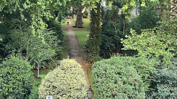 A private garden with a paved path leading to a bench area. - Charming 1-bed Apartment in London (London)