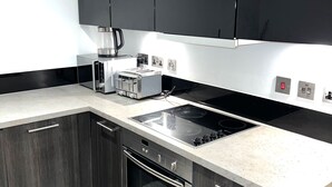 A modern kitchen with dark cabinetry, a stainless steel range, and a white countertop. - Charming 1-bed Apartment in London (London)