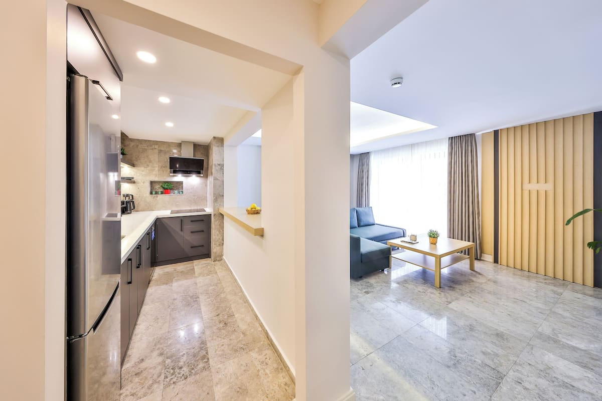 A modern kitchen with a built-in refrigerator, a microwave, and a stove. There is a dining area with a sofa and a coffee table.