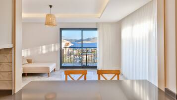 Una habitación de hotel moderna con balcón, una cama, una mesa de comedor y una lámpara colgante.