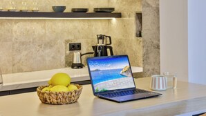Un ordinador portàtil sobre una barra de cuina amb una cistada de limones, una tassa i una cafetera al fons.