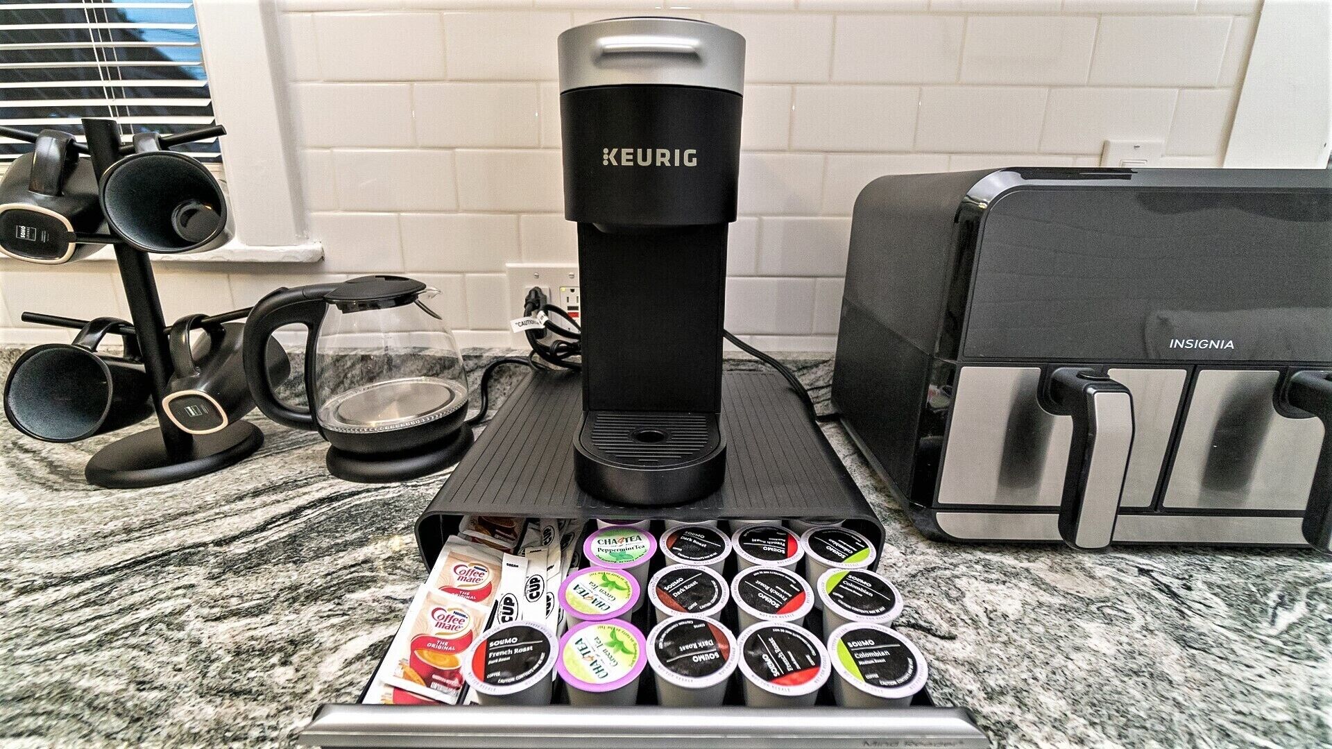A Keurig coffee maker, a coffee grinder, and a coffee machine on a kitchen counter.