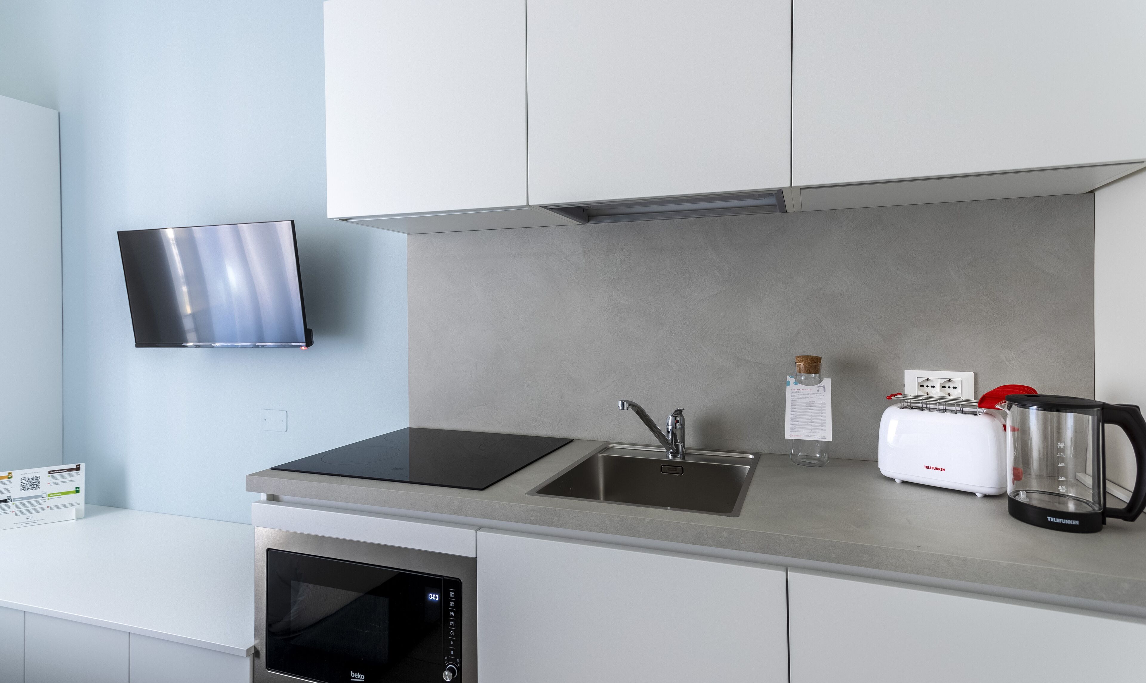 A modern kitchen with a built-in oven, a microwave, a sink, and a toaster.