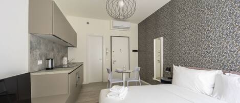 Une chambre d’hôtel moderne dotée d’un grand lit, d’une petite kitchenette, d’un coin repas et d’une salle de bain.