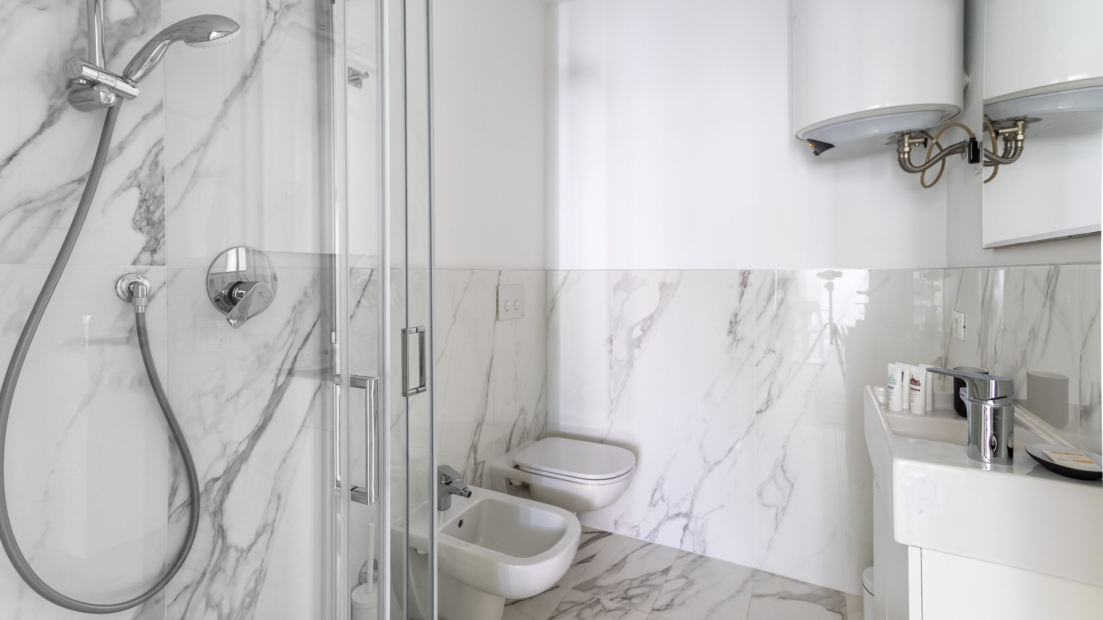 A modern bathroom with a glass-enclosed shower, a toilet, and a bidet.