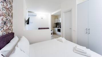 Ein modernes Hotelzimmer mit Bett, Kleiderschrank, Bad und einer Küchenzeile.