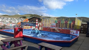 Uma área de recreação infantil com água, incluindo piscina, escorregadores e mesas para piquenique.